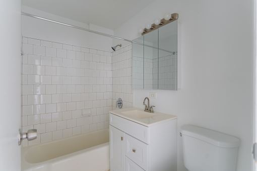 A white bathroom with a tub, sink, and mirror.
