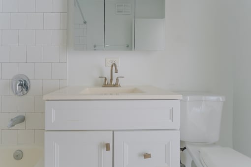 A white bathroom with a sink, mirror, and toilet.