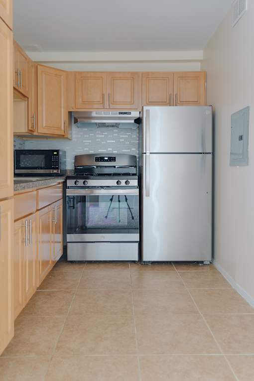 A kitchen with a refrigerator, microwave, oven, and stove.