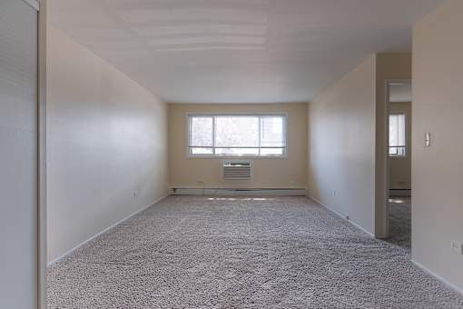 A large, empty room with a window and a door on the right side.