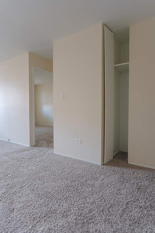 A room with carpeted floor and white walls with a doorway open.