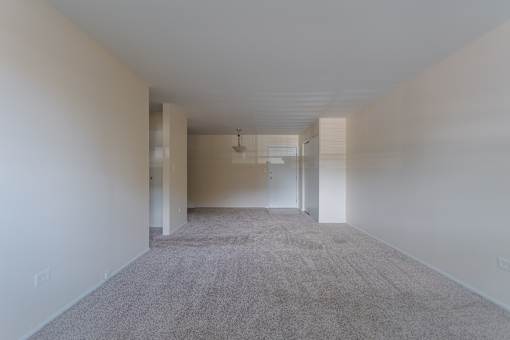 A long, empty hallway with carpeted floors and white walls.
