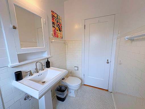 A white bathroom with a sink, toilet and a mirror.