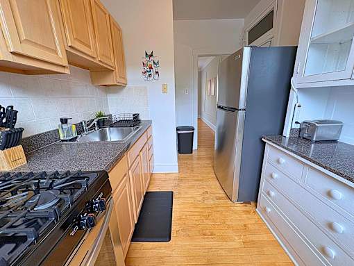 A kitchen with a black stove top oven and wooden cabinets.