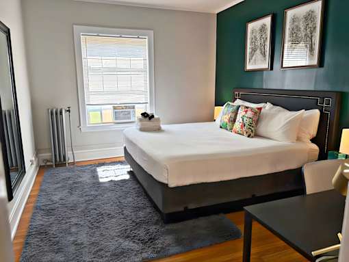 A bedroom with a large bed and a window with blinds.