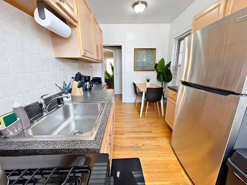 A modern kitchen with a stainless steel refrigerator and a dining area with a table and chairs.