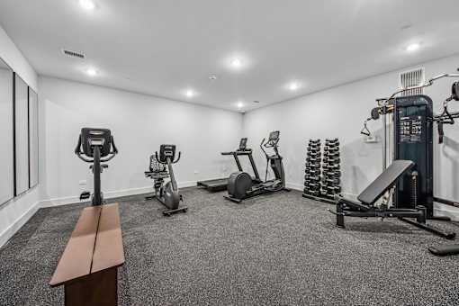 A gym with a bench, weights, and exercise equipment.