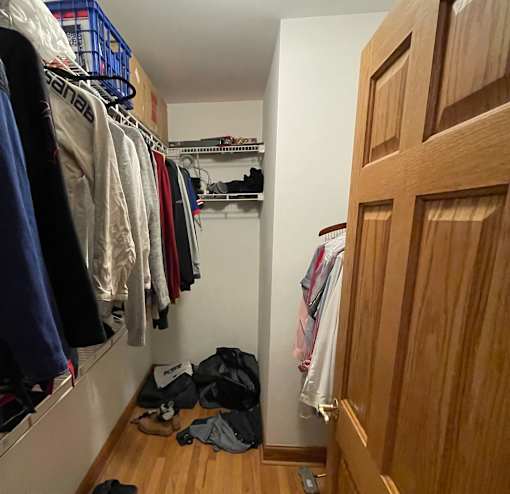 A hallway with a wooden door and clothes hanging on a rack.