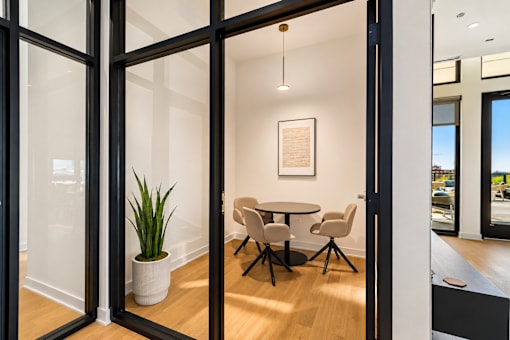 A room with a table and chairs is visible through a glass door.