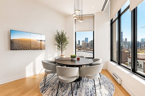 A room with a round table and chairs, a rug, and a painting on the wall.