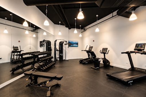 A gym with a variety of equipment including treadmills, weights, and exercise machines.