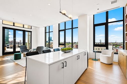 A modern office space with a large white desk and black chairs.