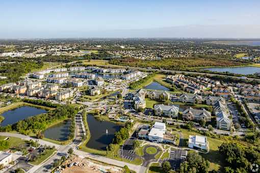 A bird's eye view of a residential area with a lake and a road.