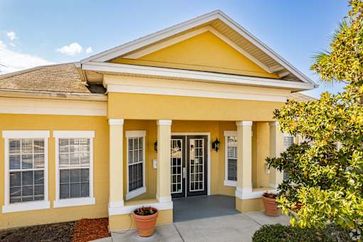 A yellow house with a brown roof and a glass door.