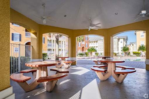 A patio with tables and chairs and a ceiling fan.