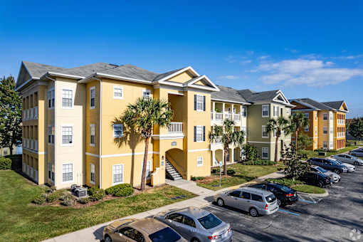 A yellow building with a parking lot in front.