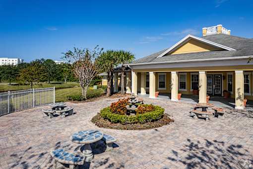 A building with a yellow roof and columns is surrounded by a circular garden with a bench.