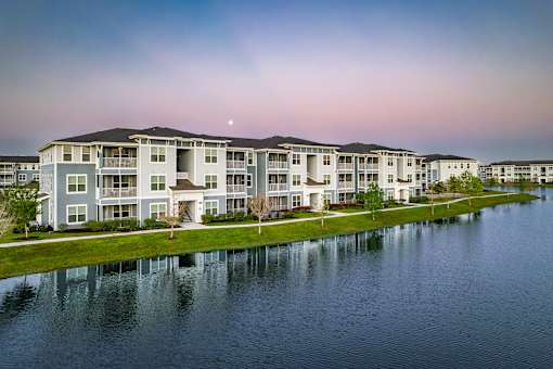 A large apartment complex sits next to a body of water.