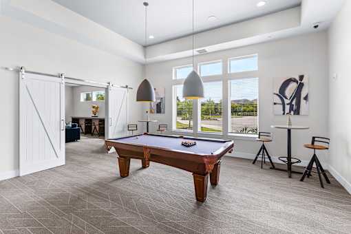 A room with a pool table and a bar stool.