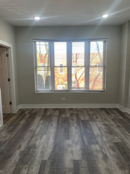 an empty living room with a window and wood floors