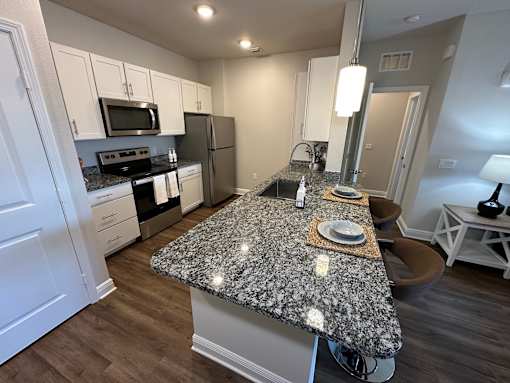 A kitchen with granite countertops and white cabinets.