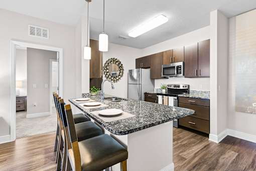 A kitchen with a granite countertop and a black chair.
