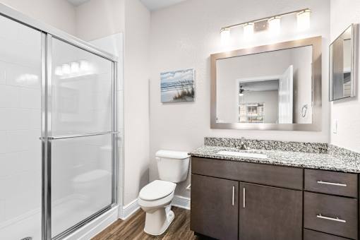 A bathroom with a toilet, sink, and a glass shower door.