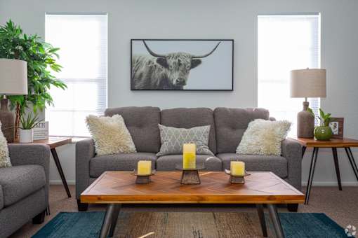 A living room with a grey couch, a wooden coffee table, and a painting of a bull on the wall.