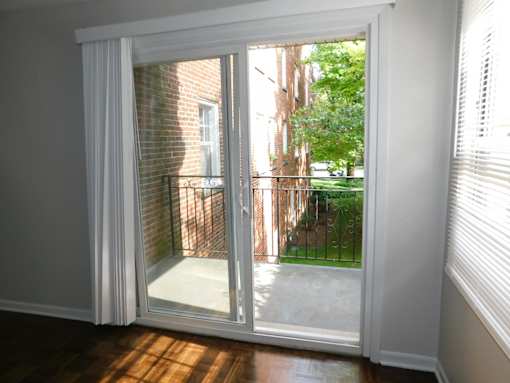 A white sliding door with a view of a backyard and a brick building.