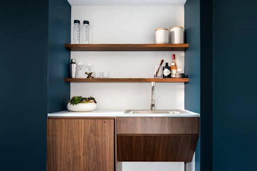 A modern kitchen with a wooden counter and shelves.