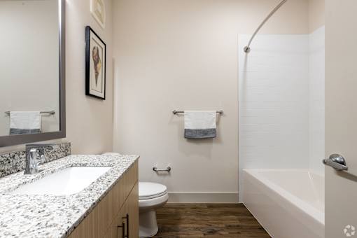 A bathroom with a white tub, sink, and toilet.