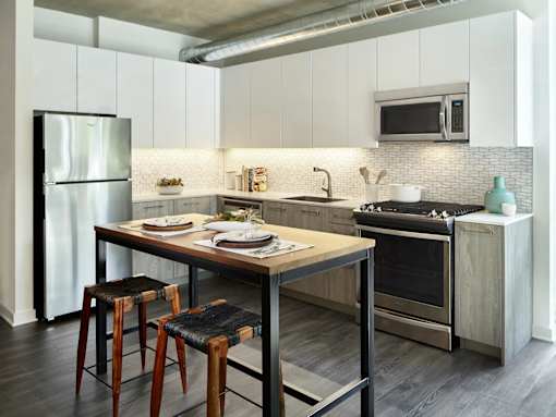 A modern kitchen with a wooden table and bar stools.