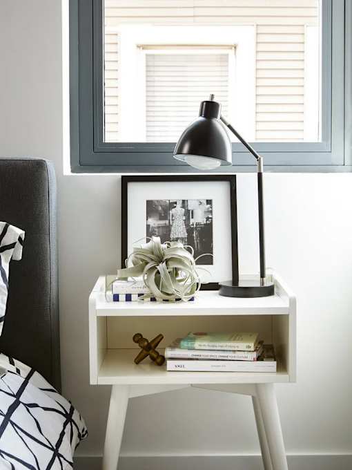 A black and white photo is framed and placed on a small white desk with a black lamp.