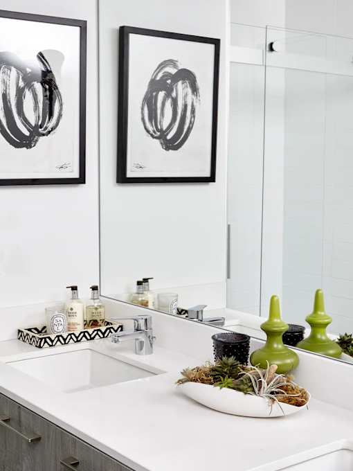 A bathroom with a white sink and two framed black and white pictures on the wall.