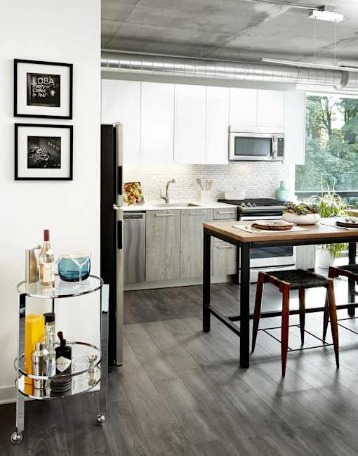 A kitchen with a black fridge, a wooden table and a bar cart.