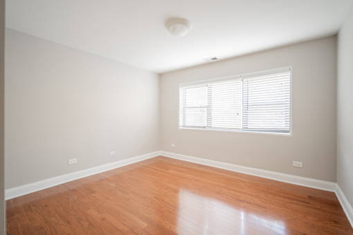 A room with wooden floors and a window with blinds.