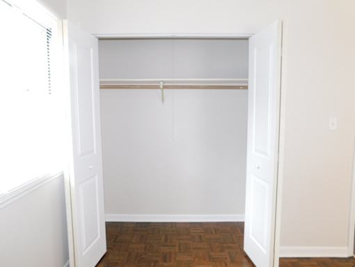 A white closet with a wooden floor and a window.