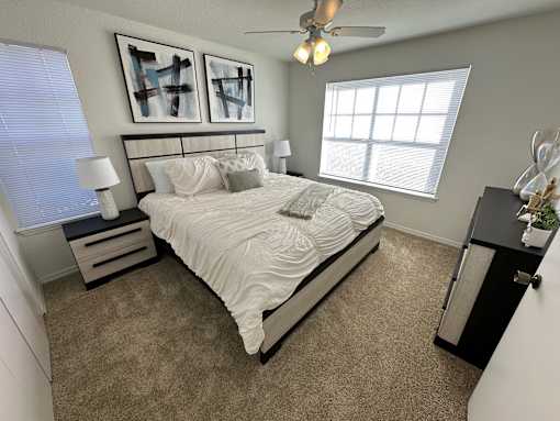 A bedroom with a bed, nightstand, and two framed artworks on the wall.
