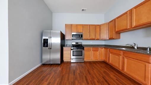 A kitchen with wooden cabinets and a stainless steel refrigerator.