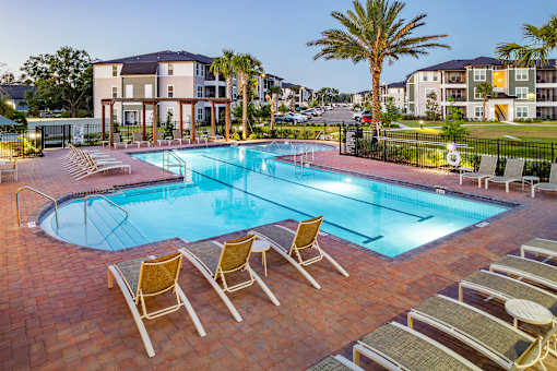 A swimming pool surrounded by lounge chairs and palm trees.