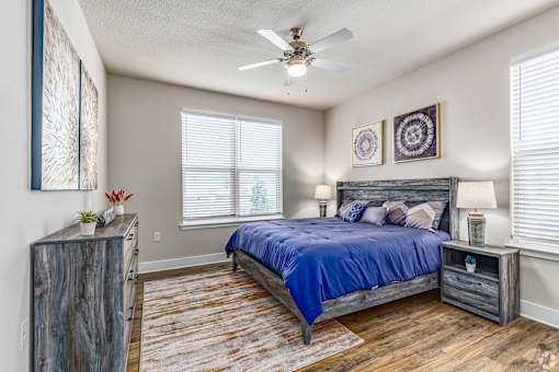 A bedroom with a bed, nightstand, and a ceiling fan.