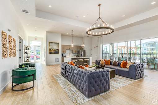 A modern living room with a green sofa and a grey tufted ottoman.