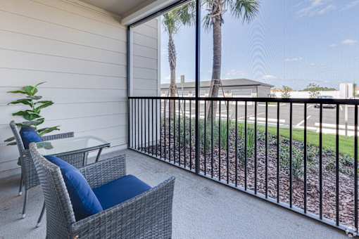 A balcony with a chair and a table with a blue cushion.