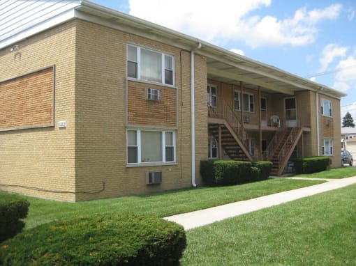 a brick apartment building with stairs and a lawn