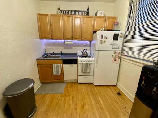 A small kitchen with a white fridge and wooden cabinets.