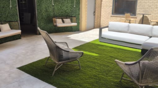 A patio with a white couch, a green rug, and a chair.