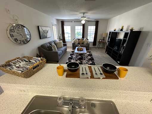 A kitchen with a clock on the wall and a dining table set for two.