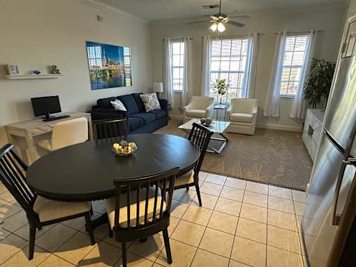 A black table with four chairs around it in a room with a blue couch and a painting on the wall.