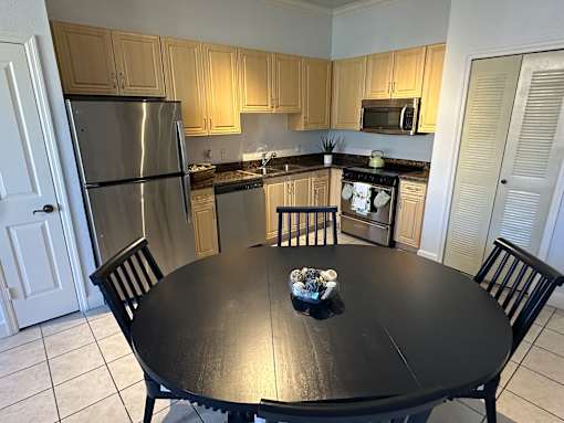 A kitchen with a table in the middle and chairs around it.