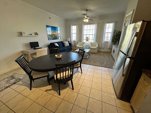 A black table with four chairs is in the middle of a kitchen and dining room.